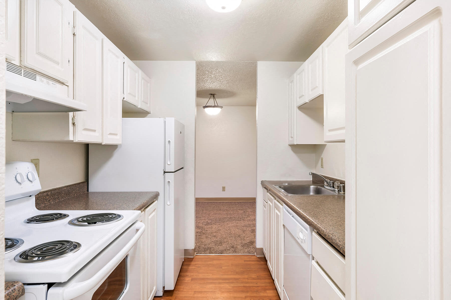 A white kitchen leading into a dining room Arbor Park Apartment Homes in Seattle, Washington.